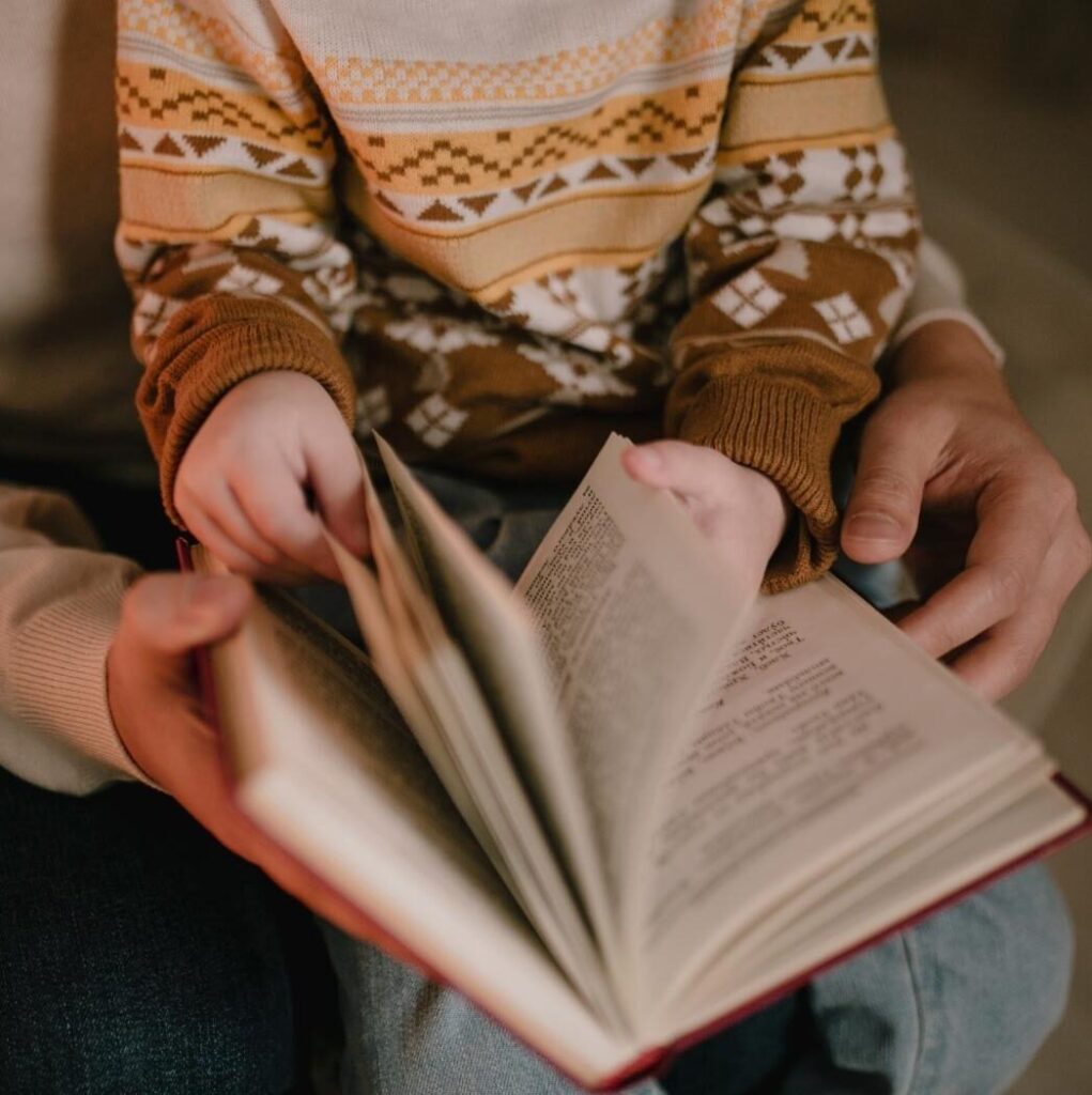 Closeup of a child on his parents lap, flipping through a book together