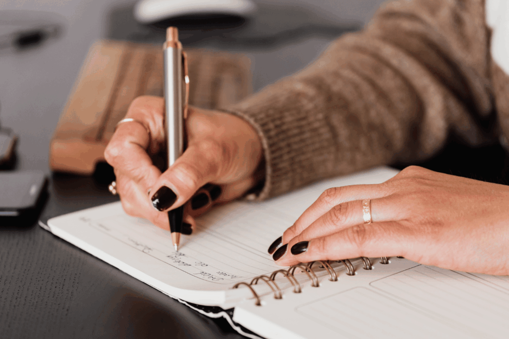 A closeup of a woman writing in her notepad