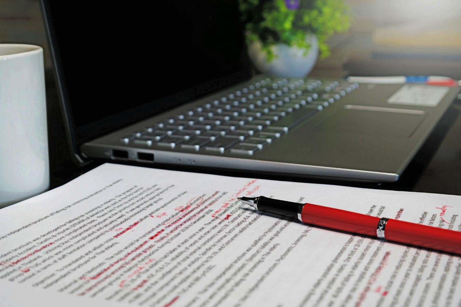 Red marked page sits by a laptop