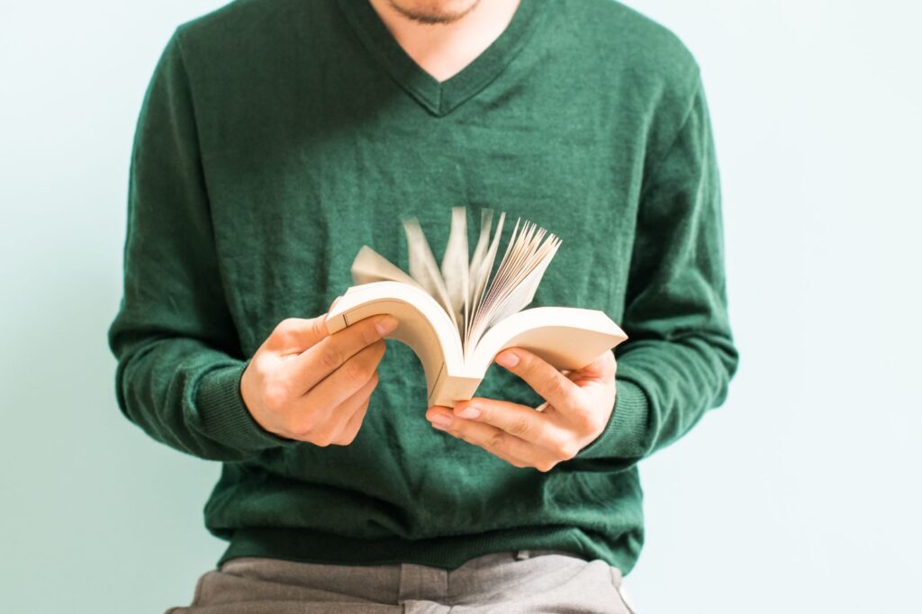 Man in green sweater flipping through a book