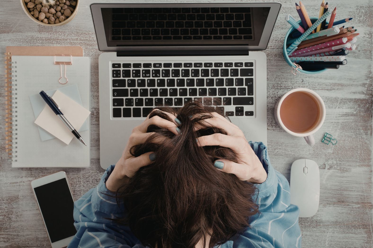 Frustrated woman sits are her desk with her hands on her head