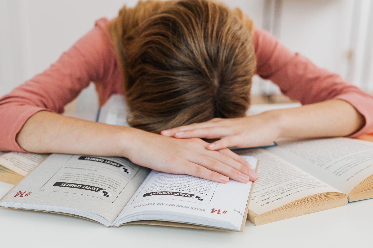 Woman lying on her books, feeling as if she's failed.